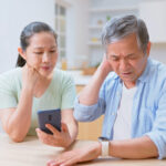 asian elderly couple use smartphone connected with smart watch to track health - they feel worried